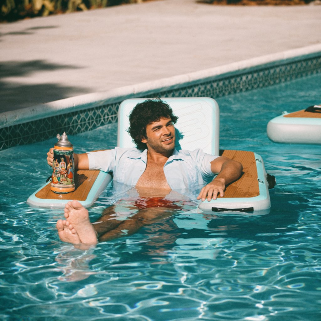 A guy sitting in the Inflatable Hangout Chair Classic in the pool