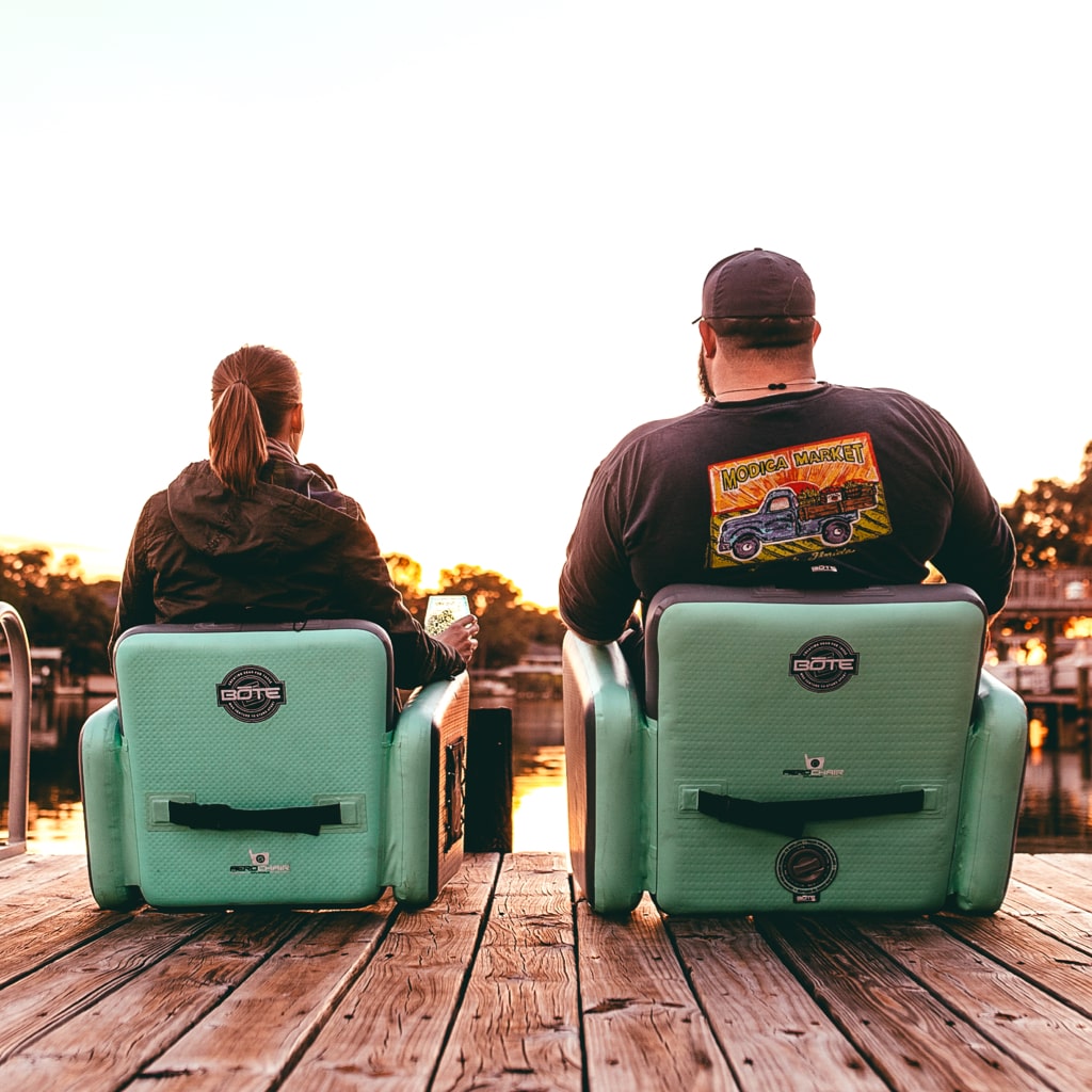 Two people sit side-by-side, one in the Aero Chair XL on the right and the other in the Aero Chair on the left.