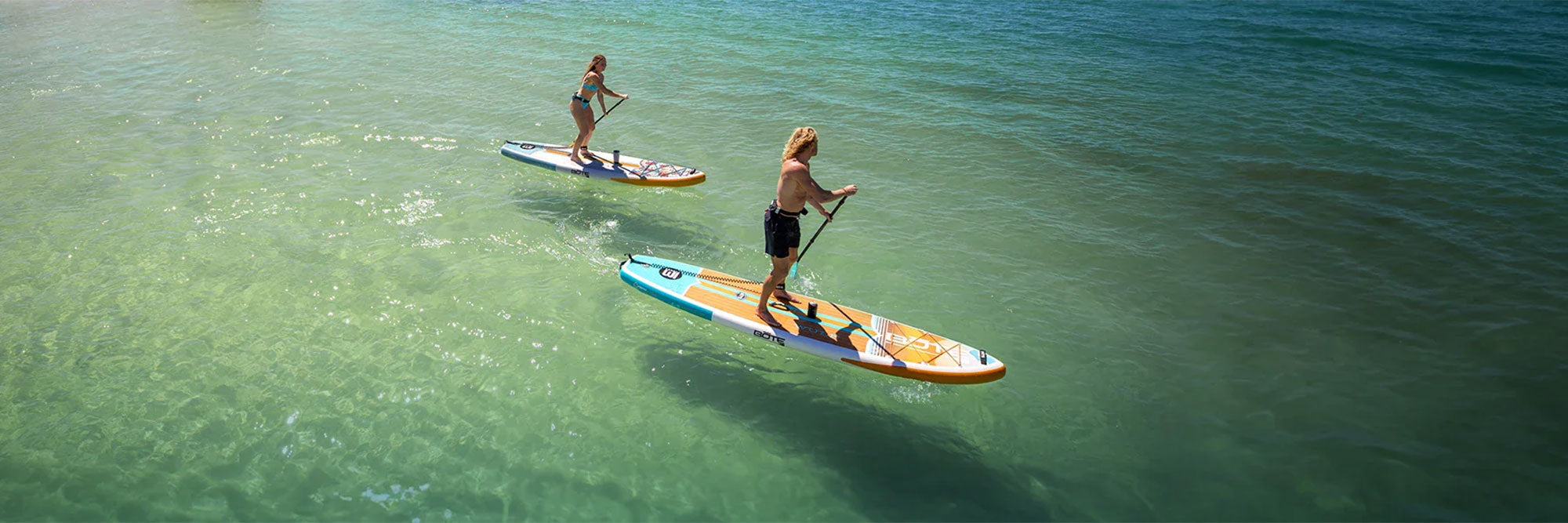 Two people paddling on paddle boards on calm water