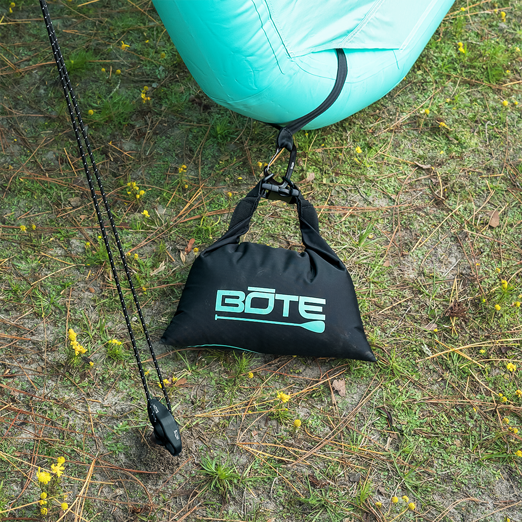 Top view of Anchor Kit clipped to an aqua inflatable float on grass.
