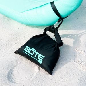 Angled view of Anchor Kit clipped to an aqua inflatable float on sand.