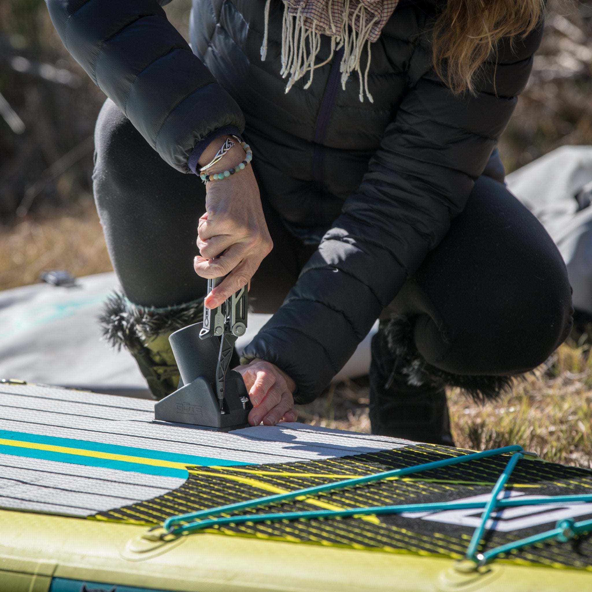Person using multitool to install Screw-In Aero Rac Receiver on paddle board deck.