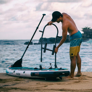 Man attaching Tackle Rac to board using Screw-In Aero Rac Receivers on sandy shoreline.